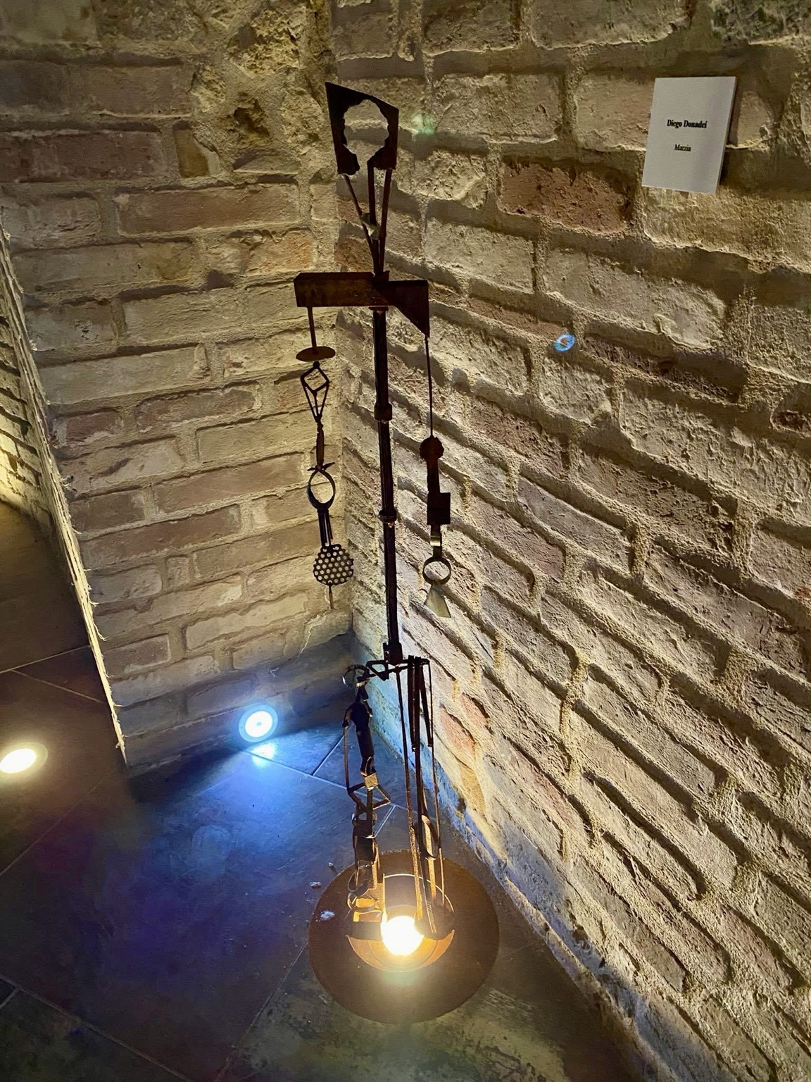 Assemblaggio in ferro illuminato davanti alla parete in mattoni